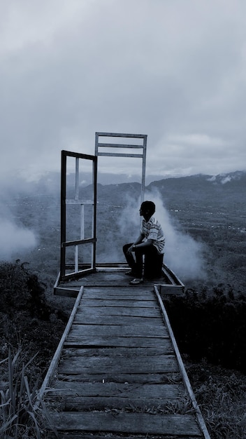 Rear view of man walking on boardwalk against sky