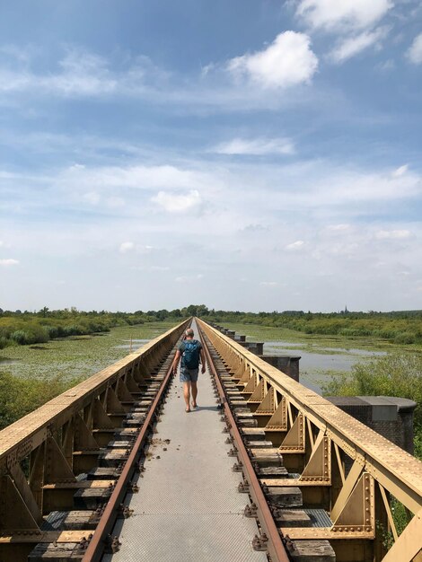 Photo rear view of man walking on bridge against sky