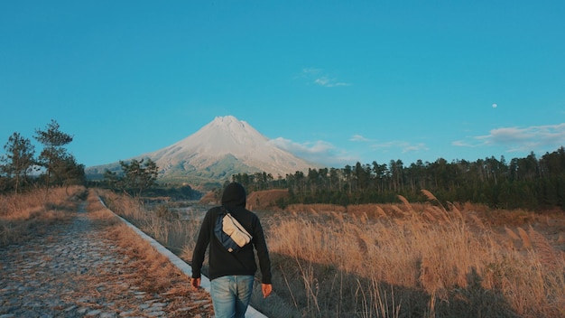 Photo rear view of man walking by field on road