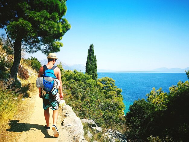 Photo rear view of man walking by sea against clear sky