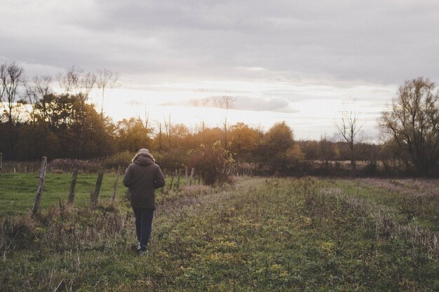 Photo rear view of man walking on field against sky