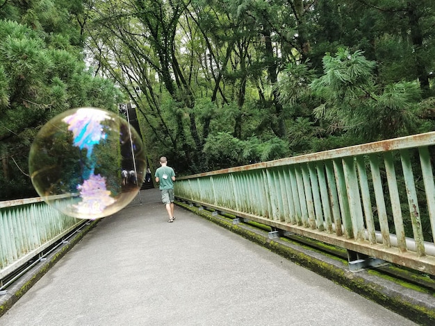 Rear view of man walking on footbridge