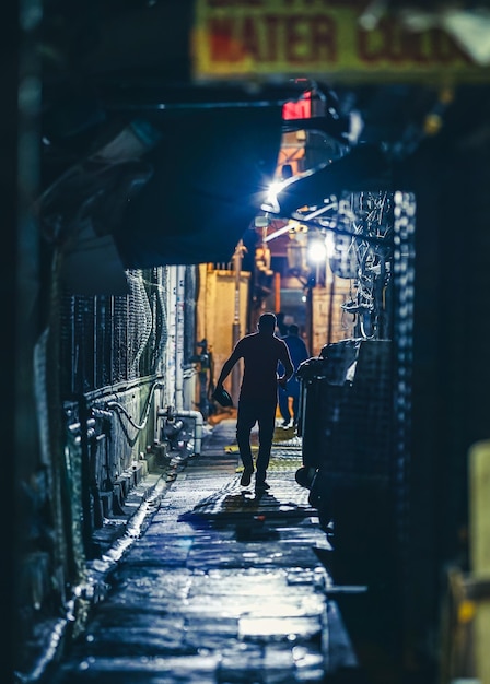 Photo rear view of man walking on footpath amidst buildings in city