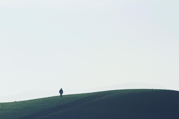 Photo rear view of man walking on grassy field