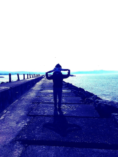 Photo rear view of man walking on jetty against seascape