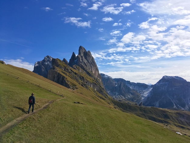 rear view of man walking on mountain against blue sky