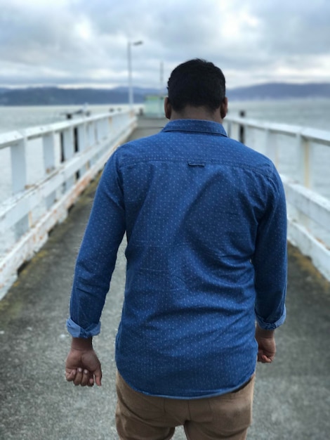 Photo rear view of man walking on pier over sea