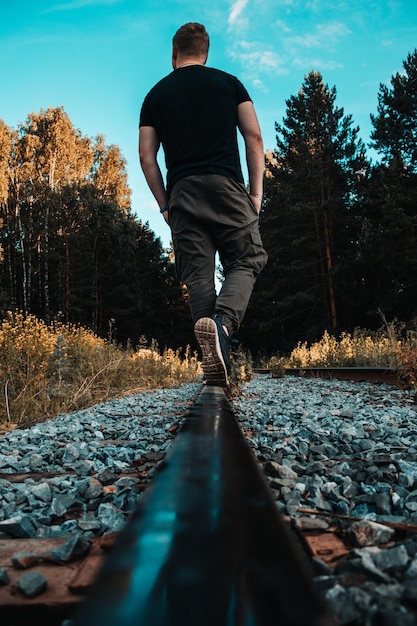 Rear view of man walking on railroad track