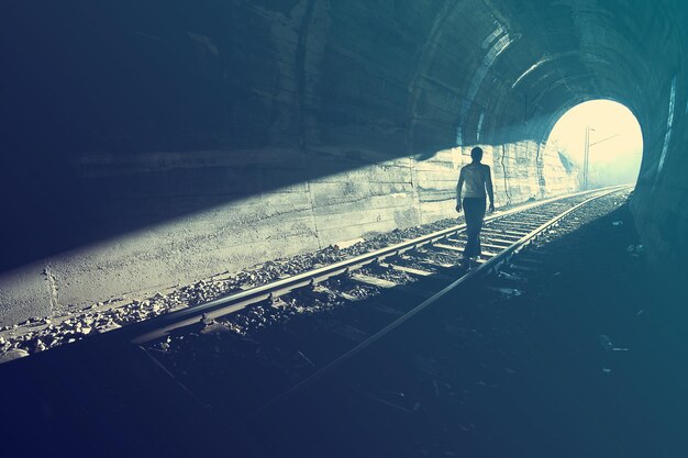 Foto vista posteriore di un uomo che cammina sui binari della ferrovia in un tunnel