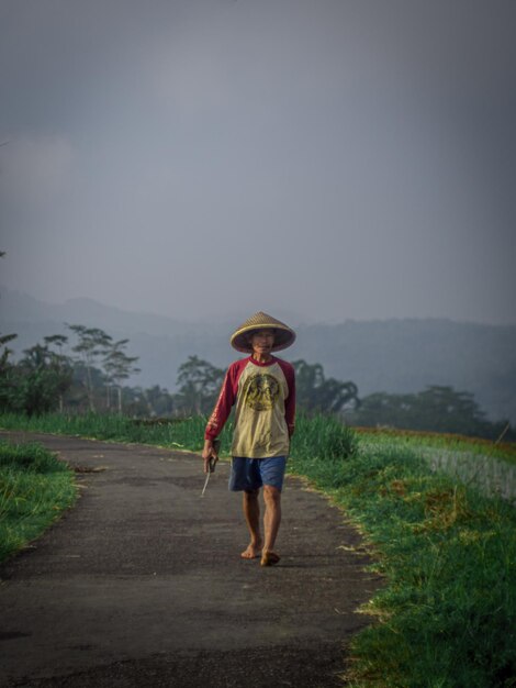 Rear view of man walking on road against sky