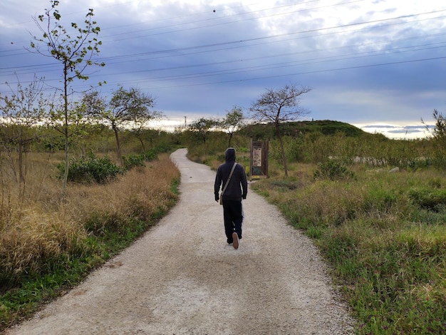 Photo rear view of man walking on road against sky