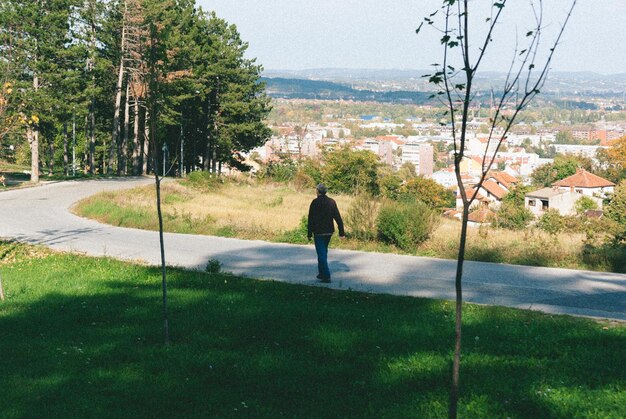 Foto vista posteriore di un uomo che cammina sulla strada contro la città