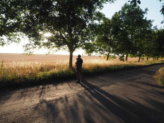 Rear view of man walking on road against trees