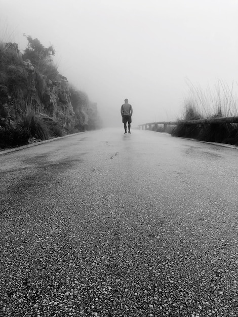 Photo rear view of man walking on road during foggy weather