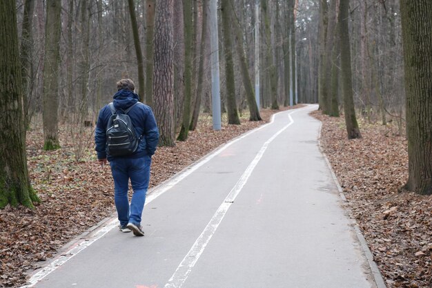 Photo rear view of man walking on road in forest