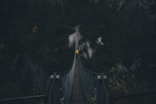 Foto vista posteriore di un uomo che cammina su un ponte di corde