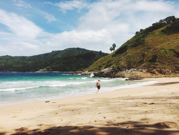 Photo rear view of man walking on shore at beach