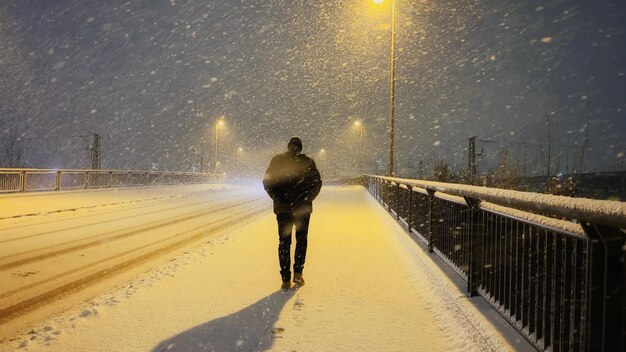 Rear view of man walking on snow covered road