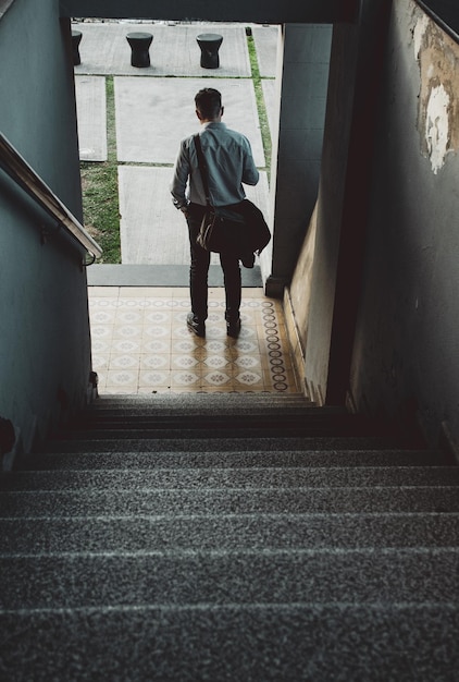 Rear view of man walking on staircase of building