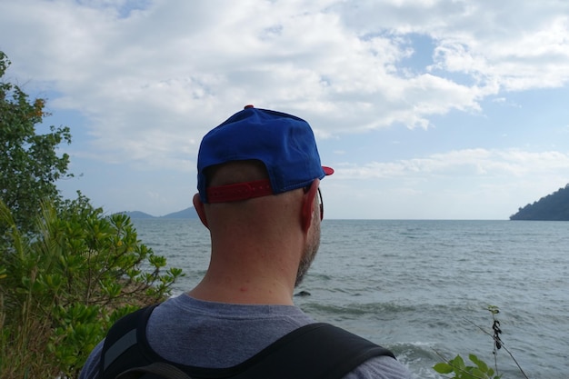 Photo rear view of man wearing cap by sea against sky