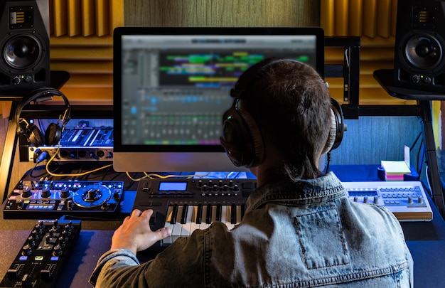 rear view of man wearing headphones working on sound mixer at studio