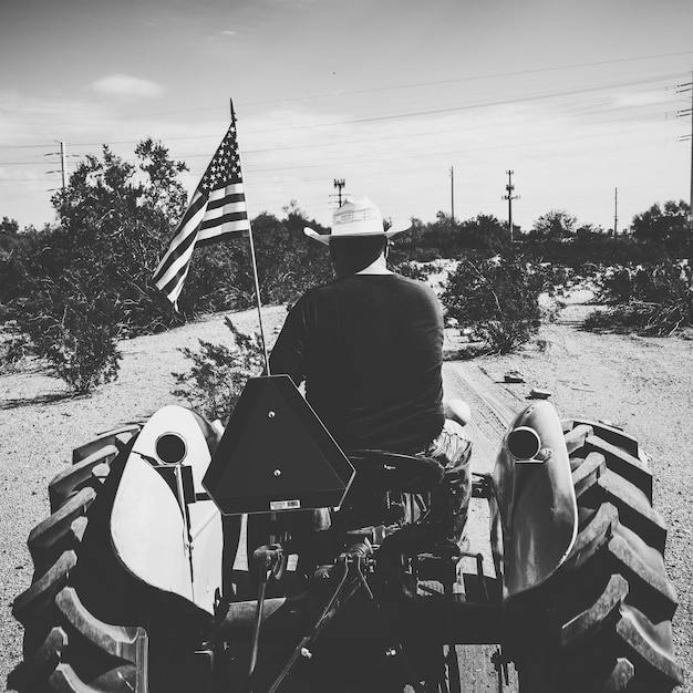 Photo rear view of man with american culture on tractor