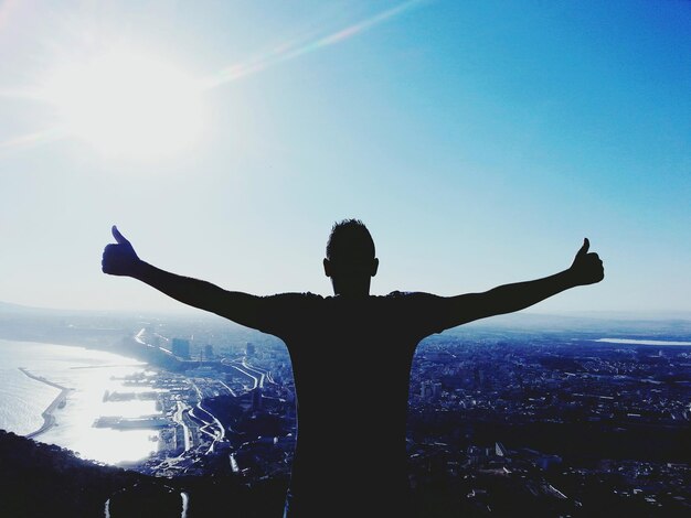 Photo rear view of man with arms outstretched against sky