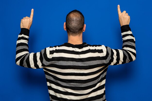 Photo rear view of man with arms raised against blue background