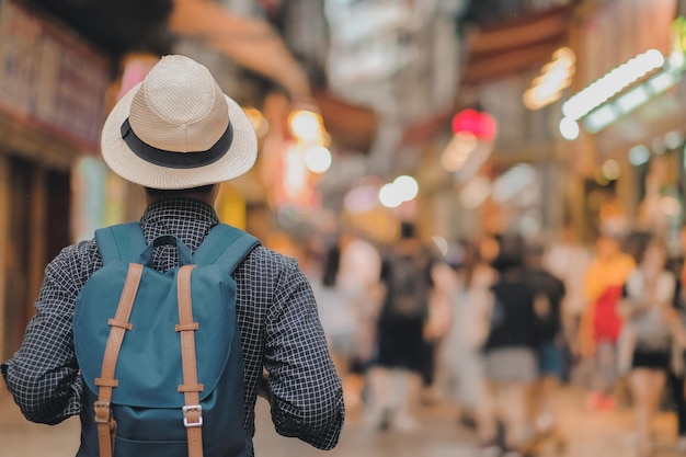 街で歩いているバックパックを背負った男の後ろの景色