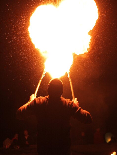 Foto vista posteriore di un uomo con cracker di fuoco di notte