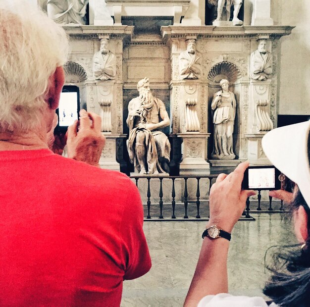 Foto vista posteriore di un uomo e una donna che fotografano una scultura