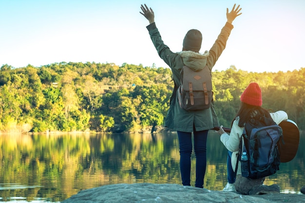 Photo rear view of man and woman standing by lake against clear sky