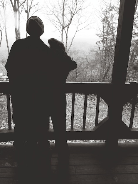 Foto vista posteriore di un uomo e una donna in piedi accanto a una ringhiera di legno