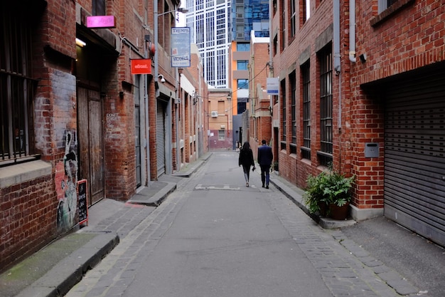 Rear view of man and woman walking on street amidst buildings