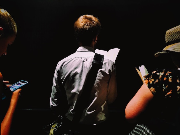 Photo rear view of man and women against black background