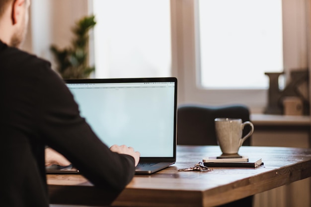 Photo rear view of man working on laptop at desk