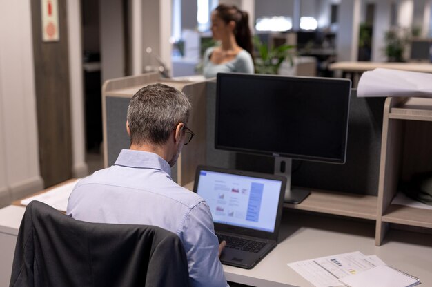 Photo rear view of mature caucasian businessman using laptop while working at modern workplace