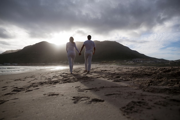 Rear view of mature couple holding hands while walking