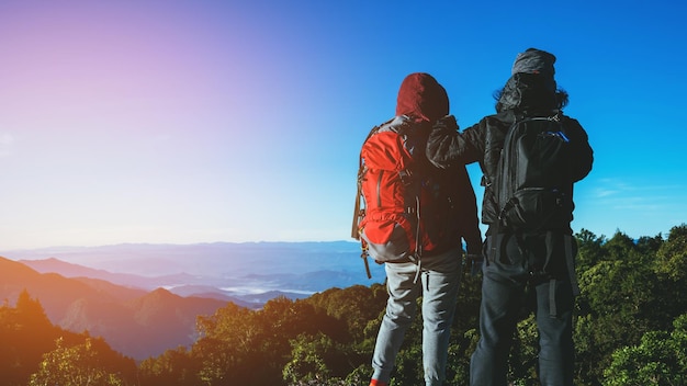 Rear view of men standing on mountain against sky