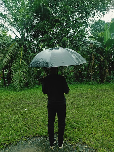 Foto vista posteriore di uomini con l'ombrello in piedi sul campo