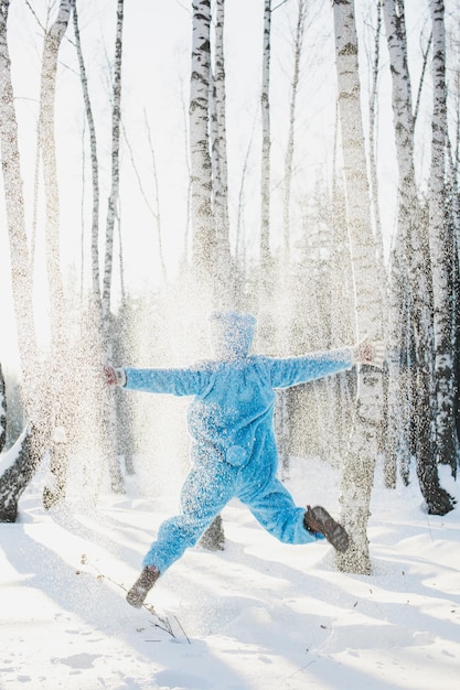 森の雪で覆われた畑でジャンプする中年成人の後ろの景色