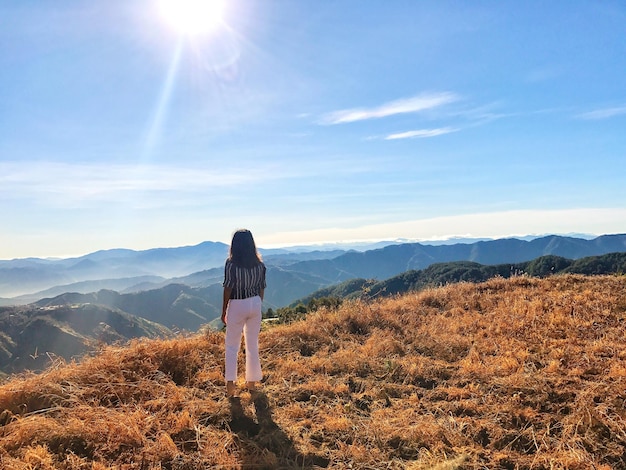 Rear view of mid adult woman standing on mountain against sky