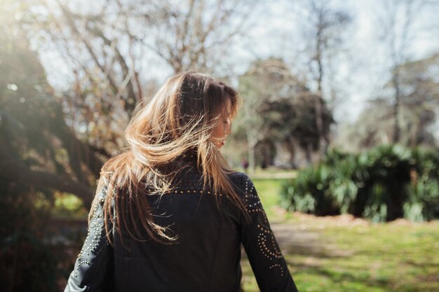 Foto vista posteriore di una donna adulta di mezza età con i capelli marroni in piedi contro gli alberi nel parco