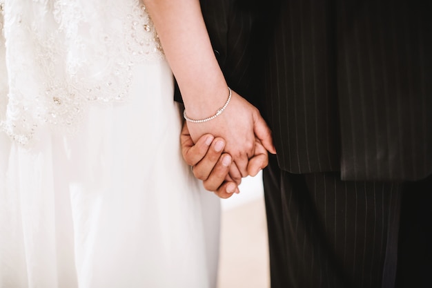 Rear view midsection of the bride and groom holding hand