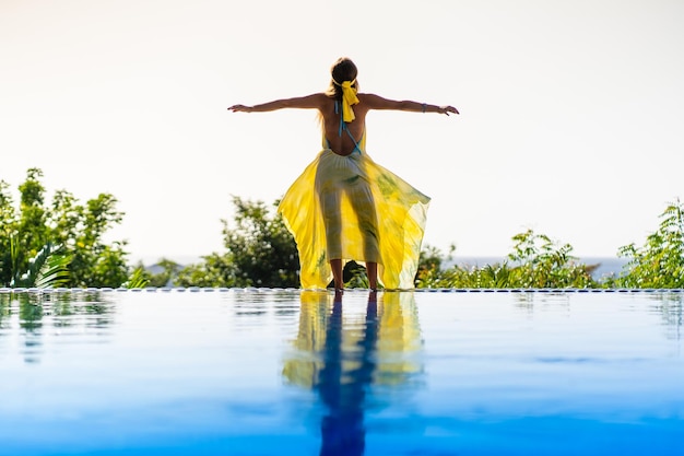 Rear view of a model standing on the edge of an outdoor tropical pool