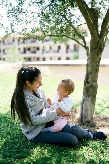 Rear view of mother and daughter sitting on tree