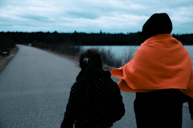 Foto vista posteriore di una madre e una figlia in piedi sulla strada durante il tramonto