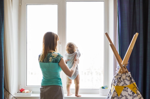 Foto vista posteriore di madre e figlio in piedi vicino alla finestra