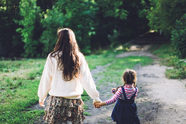 Rear view of mother with daughter on footpath