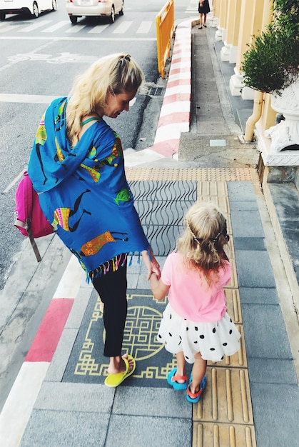 Foto vista posteriore di una madre con la figlia che cammina sul sentiero in città